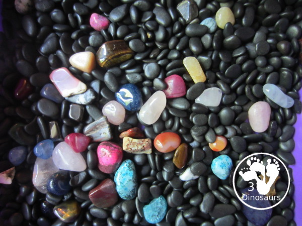 Rock Sensory Bin - a simple rock sensory bin with different shapes and colors of rocks with black rocks as filler for the sensory bin. 3Dinosaurs.com