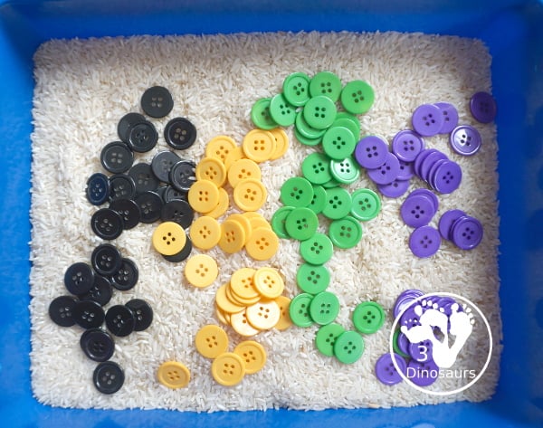 Halloween Button Black, Orange, Green & Purple Sensory Bin - is a simple button sensory bin with Halloween colors for black, orange, purple and green. They are in a rice filled for the base - 3Dinosaurs.com