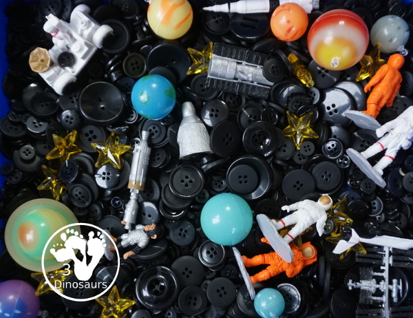 Space Button Sensory Bin - a simple sensory bin for a space theme with planets, space figures and stars in a black button filler for the sensory bin. 3Dinosaurs.com