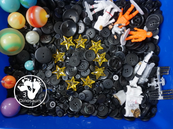 Space Button Sensory Bin - a simple sensory bin for a space theme with planets, space figures and stars in a black button filler for the sensory bin. 3Dinosaurs.com