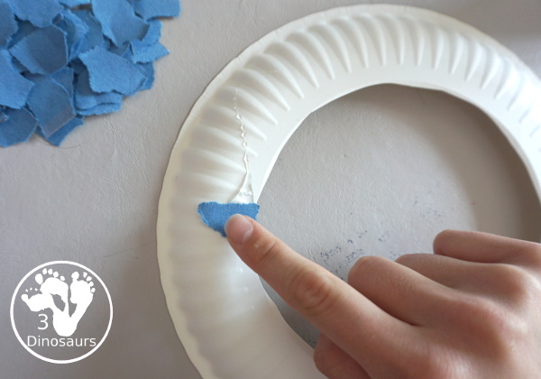 Red, White, & Blue Torn Paper Wreath is a fun wreath you can make with kids. You use torn paper of red, white, and blue glued on the wreath. A simple idea for the Fourth of July for kids. 3Dinosaurs.com