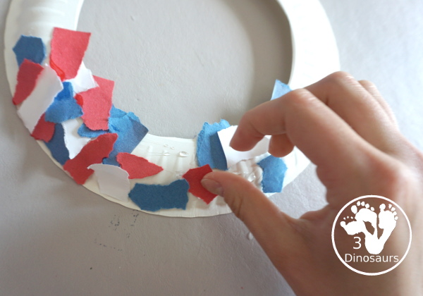 Red, White, & Blue Torn Paper Wreath is a fun wreath you can make with kids. You use torn paper of red, white, and blue glued on the wreath. A simple idea for the Fourth of July for kids. 3Dinosaurs.com