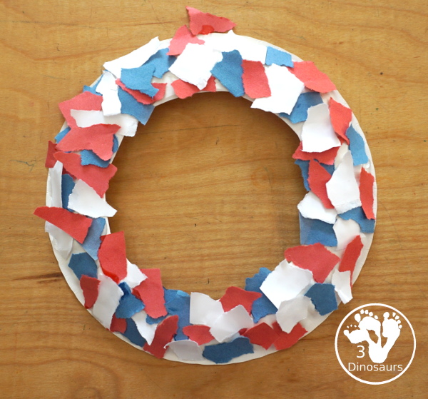 Red, White, & Blue Torn Paper Wreath is a fun wreath you can make with kids. You use torn paper of red, white, and blue glued on the wreath. A simple idea for the Fourth of July for kids. 3Dinosaurs.com