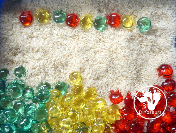 Simple Apple Sensory Bin - with acrylic apples and rice sensory bin. You have red apples, yellow apples, and green apples. This is a great sensory bin for the fall, and back to school. You can use it for any apple theme.  3Dinosaurs.com